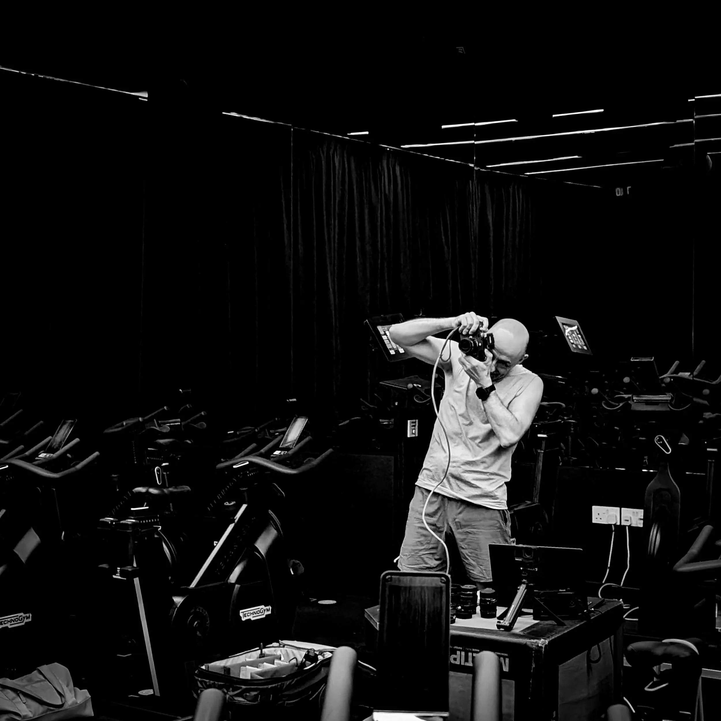 Gary McRae photographing with a Leica rangefinder in a dark spin studio, black and white